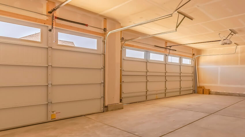 Panorama frame interior of an empty garage with two large doors small rectangular windows and round lights are installed on the unfinished ceiling
