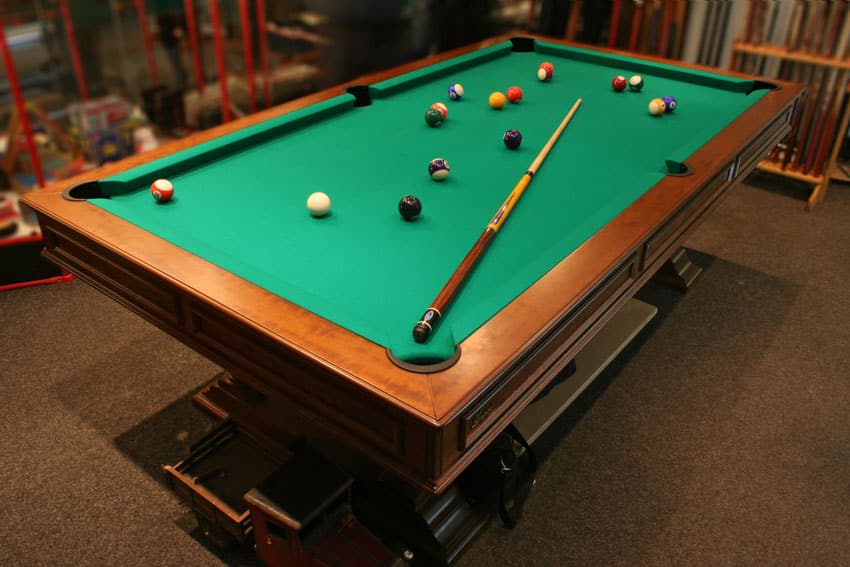 Pool table with balls and a cue stick on top of it
