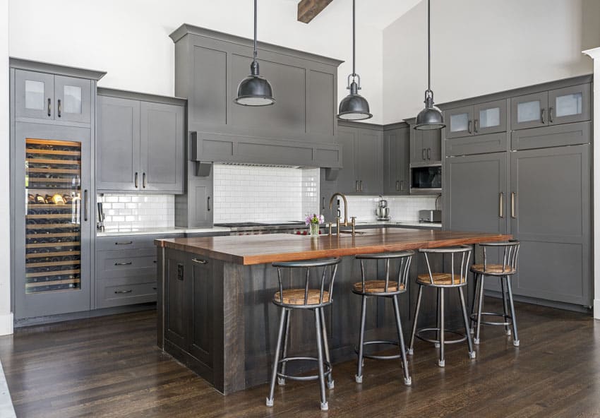 Prefab kitchen with gray cabinets, pendant light, center island, high chairs, backsplash, and countertop