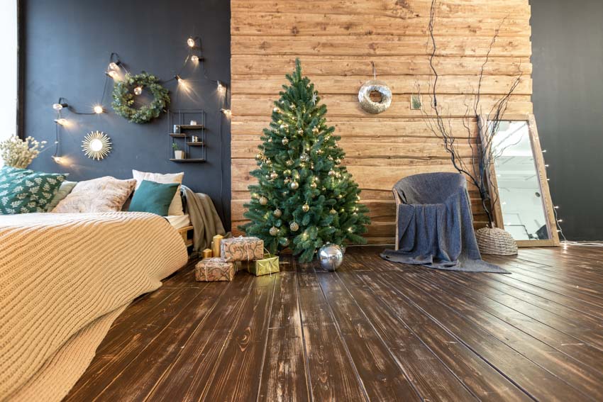 Room with small Christmas tree with dark wood flooring