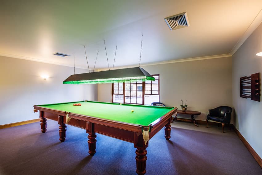 Room with hanging light, sofa chairs, and pool table
