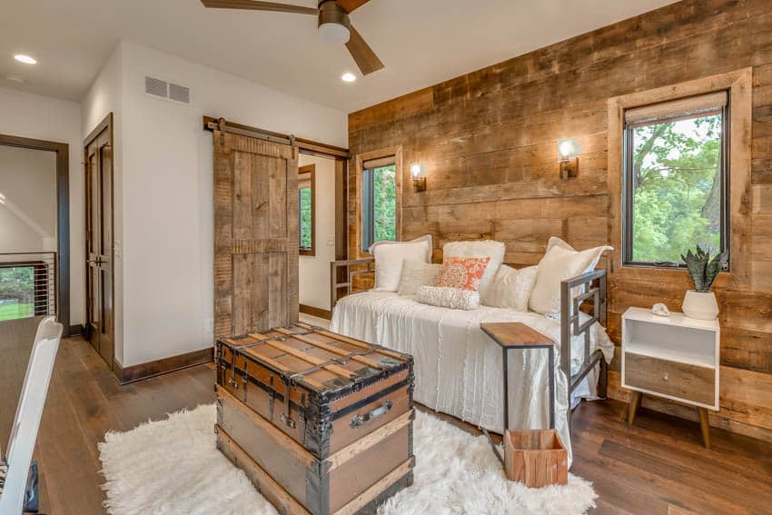 Room with rustic accent wall, couch, wood floors, and ceiling fan