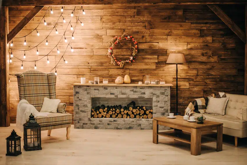 Room with hanging lights, logs, and wreath on wall