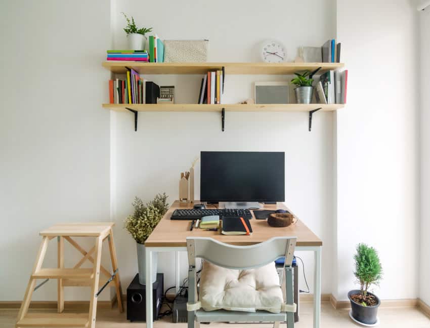 Simple home office setup with floating shelves, computer, table, and chair