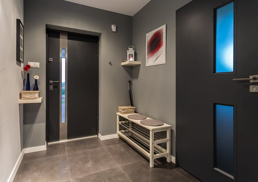 Small mudroom with grey walls ceramic grey tiles decors on walls and a bench with shelves below