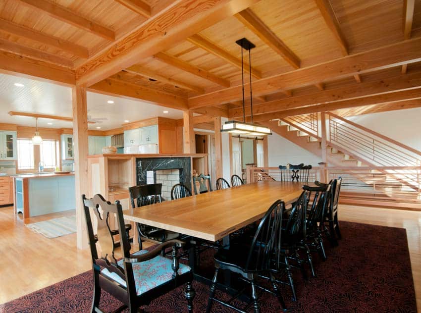 Spacious dining room with types of wood ceiling, table, chairs, floor rug, and hanging light