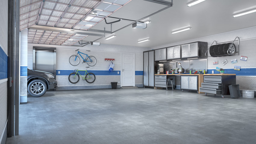 Spacious garage with lighting fixtures, concrete floor, steel cabinets, and workstation