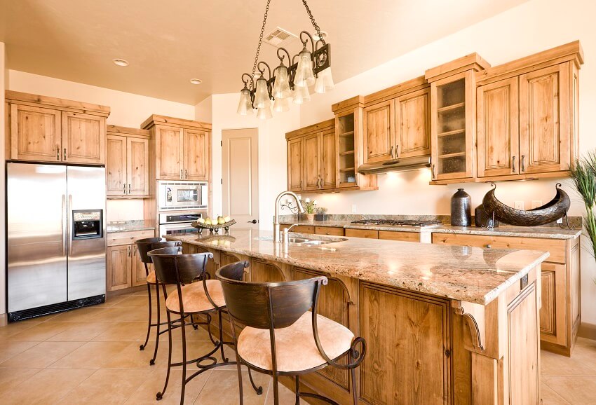 Large kitchen with knotty natural wood hickory cabinets and beige granite countertop island with rustic bar stools
