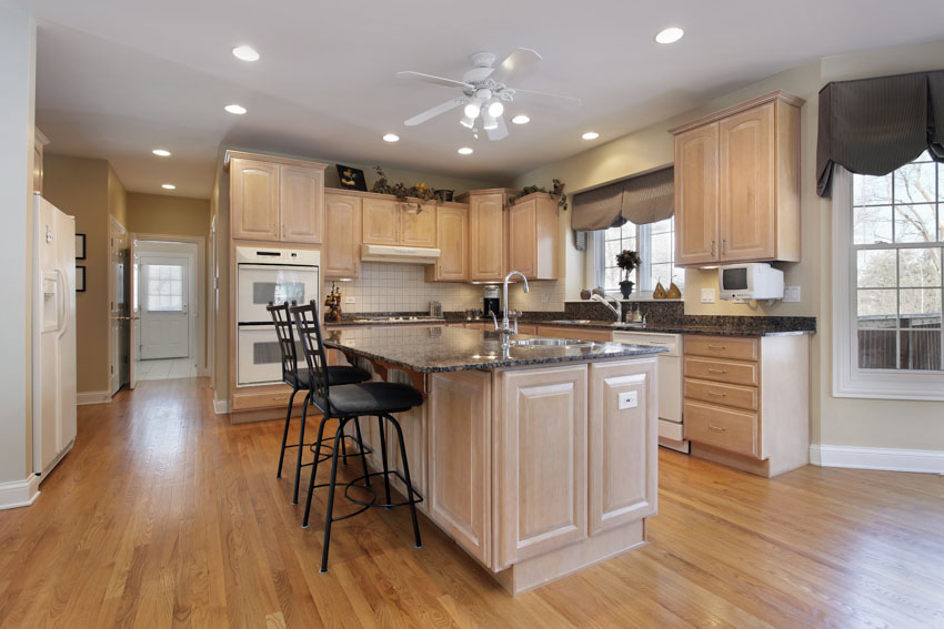 Spacious kitchen with white wood cabinets floor center island ceiling lights windows
