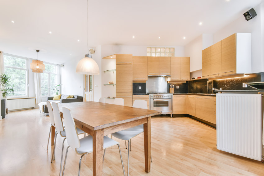 Spacious kitchen with wood floor, backsplash, cabinets, chairs, pendant lights, and recessed lighting fixtures