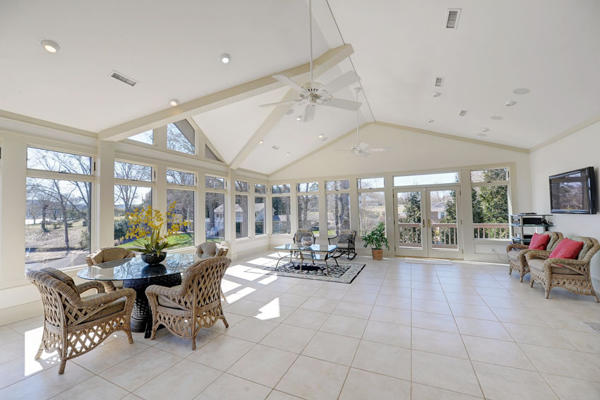 Spacious living and dining room combined tile floor sloping ceiling windows wicker chairs recessed lights ceiling fan