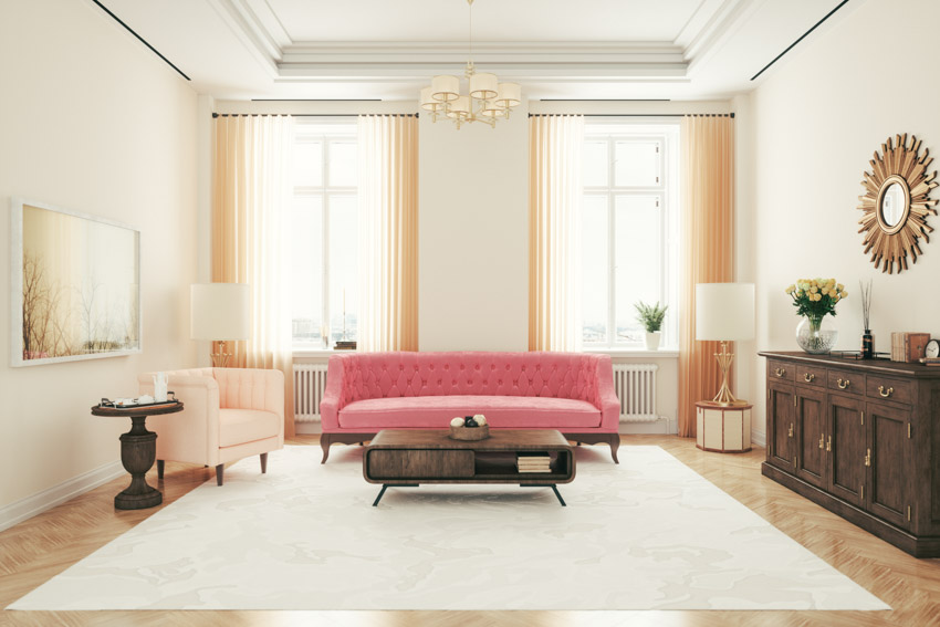 Spacious living room with pink one cushion sofa, carpet windows, floor lamps, and chandelier