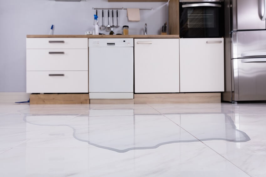 Spilled water on tile floors of a kitchen with stainless steel appliance white cabinets and wood countertop