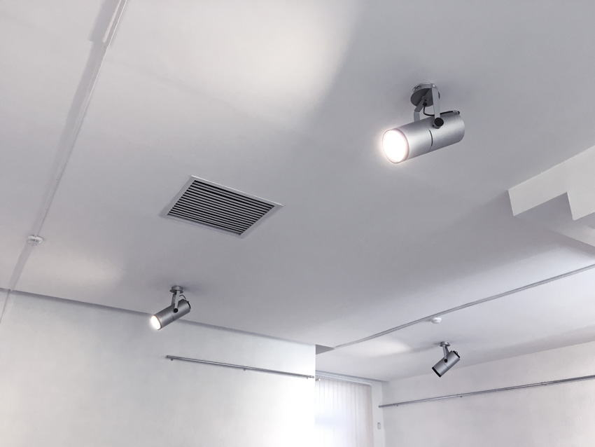 Spotlight installed on a white ceiling with air vent