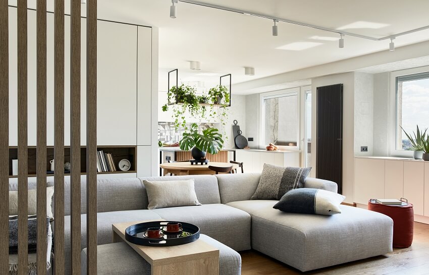 Stylish living room with wooden panels, white track lighting, grey sofa and coffee table