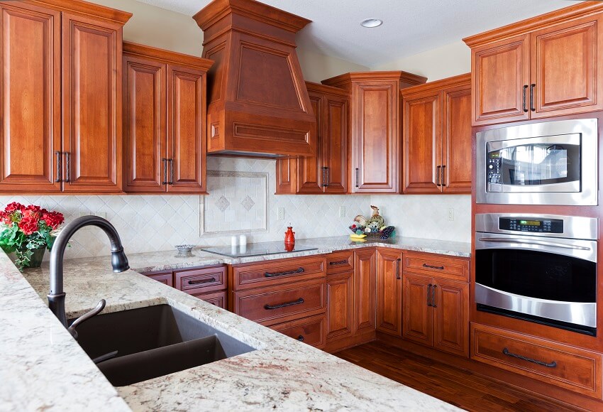 Stylish kitchen with granite countertop wooden floors stainless oven and cherry cabinets
