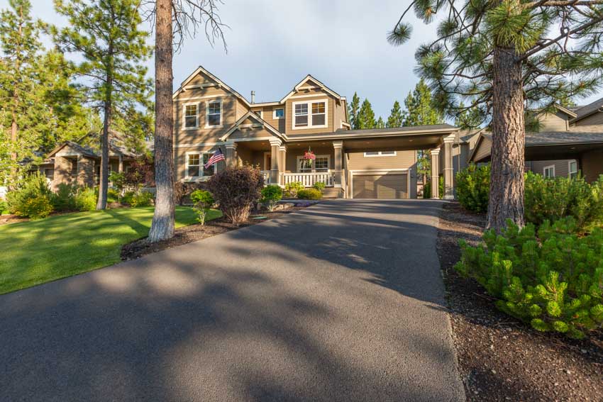 Beige colored house with long driveway and lawn