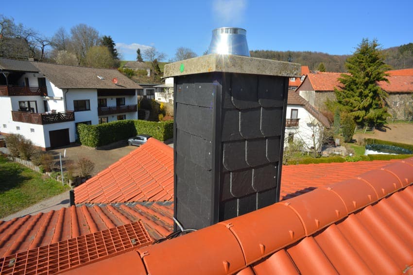 Top sealing type of fireplace damper placed on a chimney and an orange roof