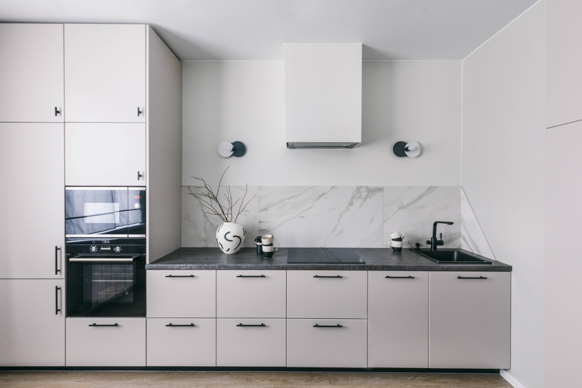 White kitchen with flat panel cabinets, and thin panel quartzite splashguard