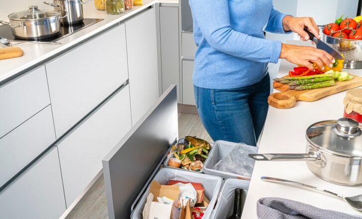 Trash Compactor Pros And Cons   Woman Chopping Vegetables In A Modern Kitchen With Trash Bins White Cabinets And White Countertops Is 728x441 