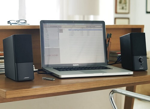 Wood desk with laptop and black Bose speakers