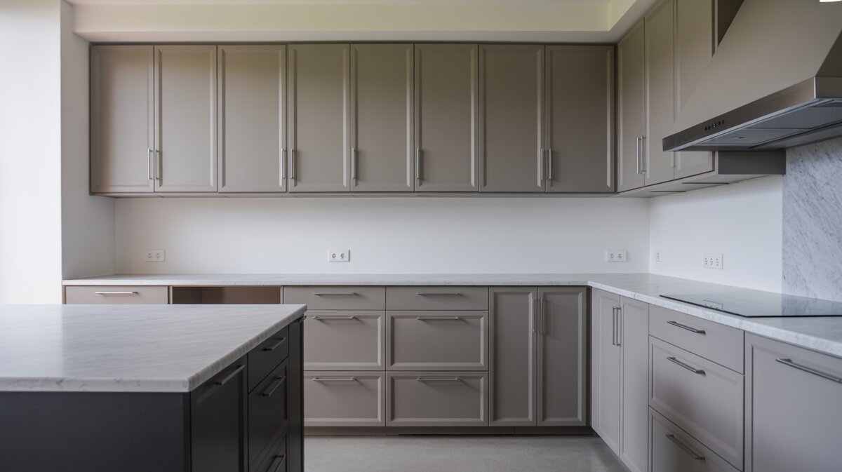 U shaped gray flat panel cabinets with marble counters and a dark island