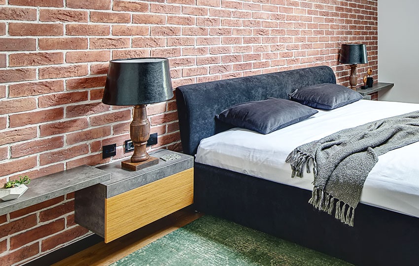 Bedroom with nightstands, black shade lamps and brick wall