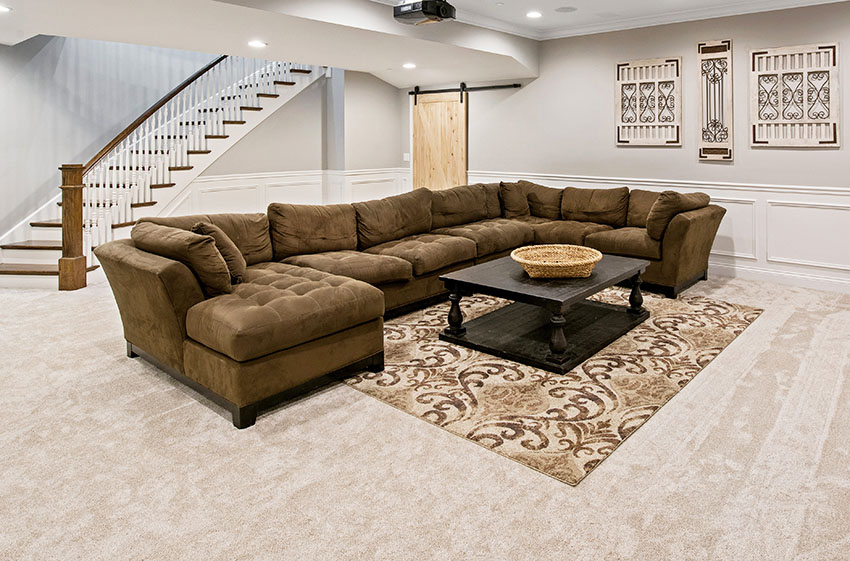 Large living area with large sectional sofa with chaise coffee table rug stairs barn doors recessed lights wall arts