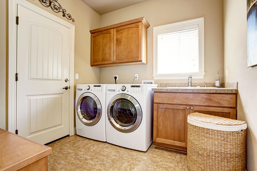 Laundry room with beige paint hanging cabinet laundry basket