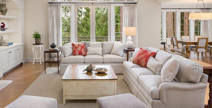 Living area with two couches with end tables lampshade rustic table brown rug French doors