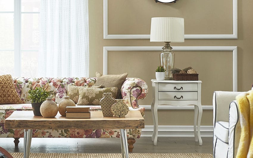 Living room with flower cushion sofa, coffee, side table with lamp and brown paint