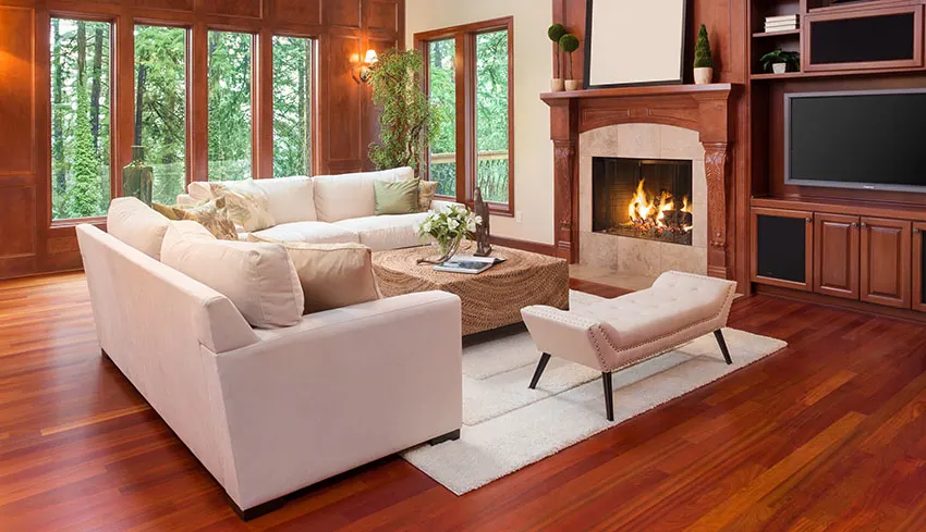 Spacious living area with fireplace sectional sofa coffee table rug picture windows red wood floors and walls