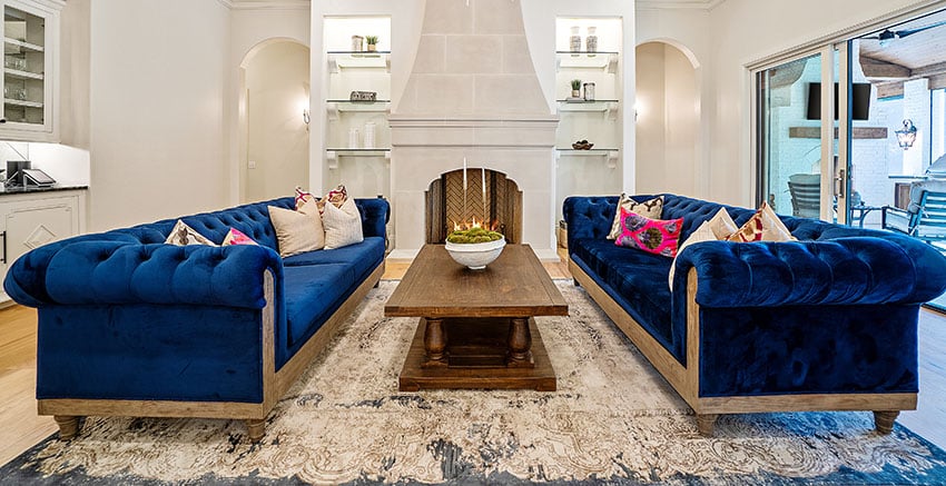 Two blue sofas facing each other with wooden coffee table fireplace