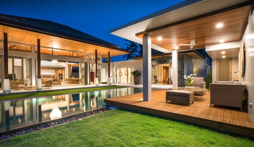 A modern house with pool, wood and concrete columns, lanai, and dining and living area in the background