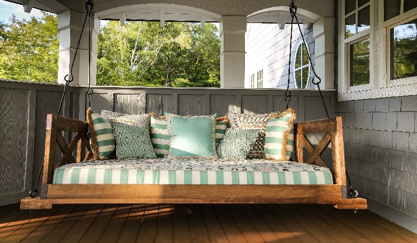 A rain porch with wood swing and throw pillows