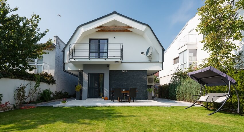 Backyard of a barndominium with patio, shaded bench, and lawn