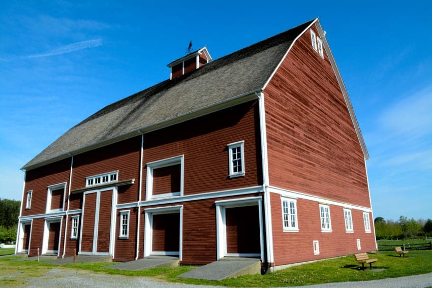 Barndominium with red exterior, white trim, pitched roof, and cupola