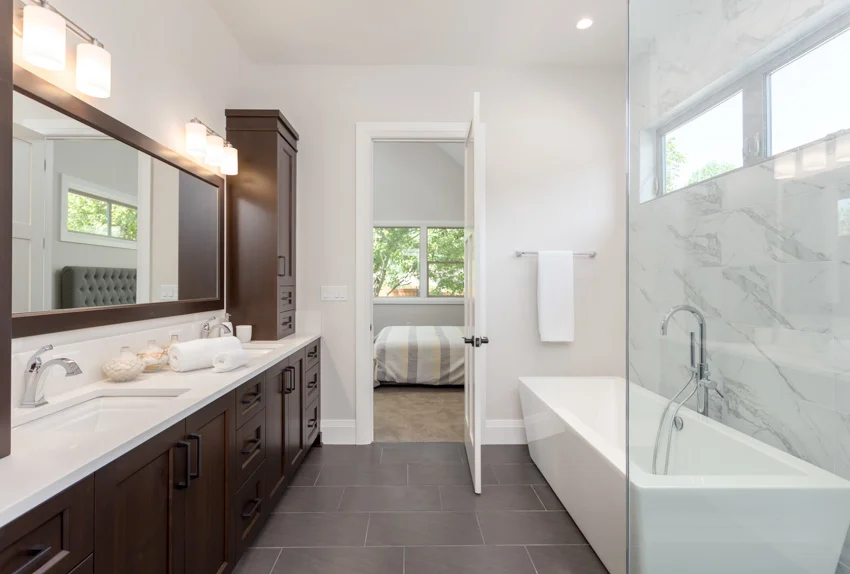 Bathroom with tile floor, white countertop, mirror cabinets, windows, and accent lighting