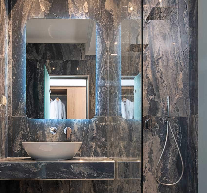 Bathroom with stone-look epoxy textured wall, lighted mirror, and basin sink