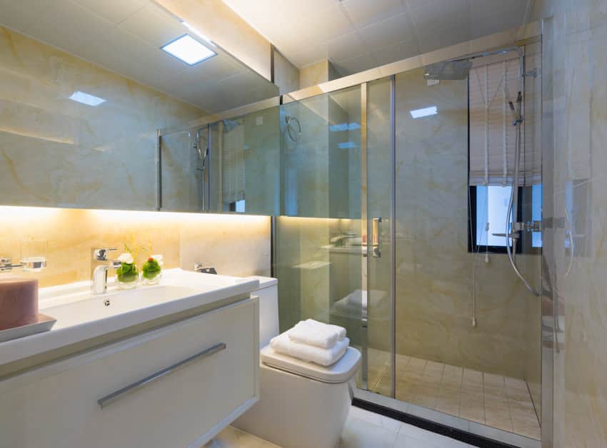 Bathroom with epoxy shower wall, glass divider, mirror, toilet, and sink