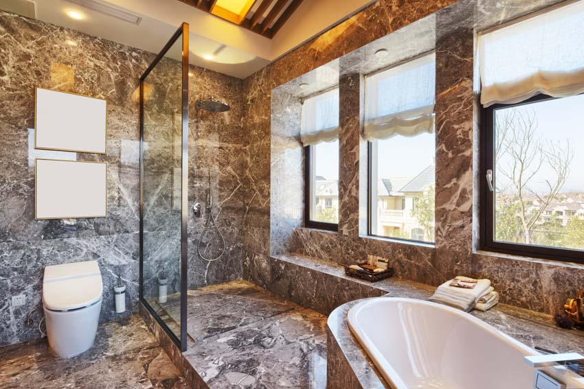 Bathroom with wall epoxy finish, tub, glass wall, toilet, and windows