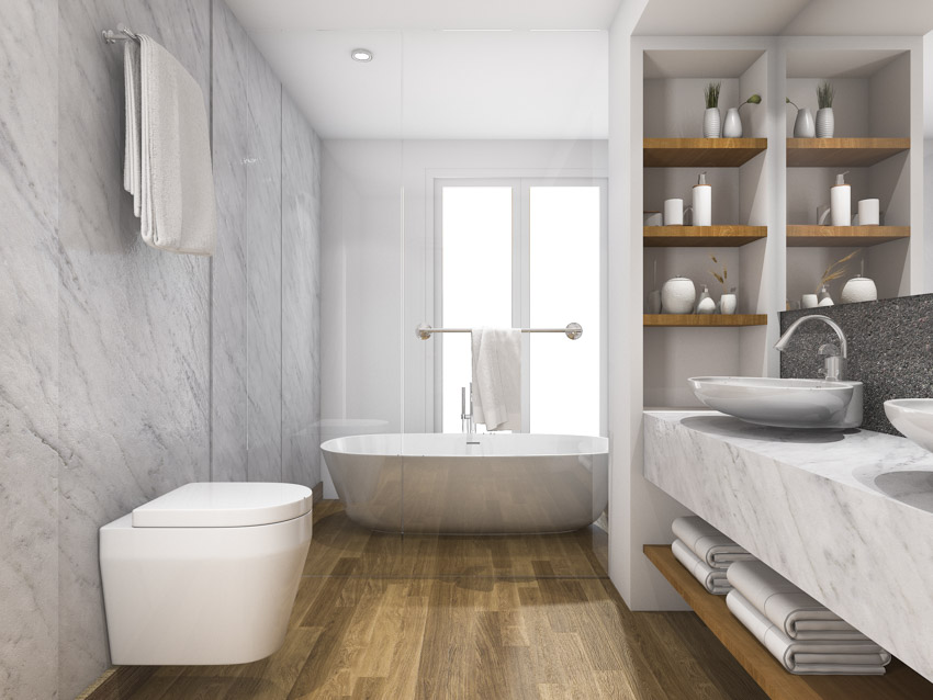 Bathroom with laminate wood flooring, tub, toilet, countertop, sink, faucet, and shelves