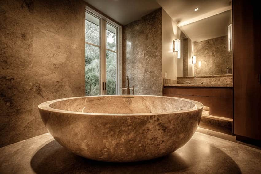 Bathroom with circular tub, mirror and large granite wall tiles