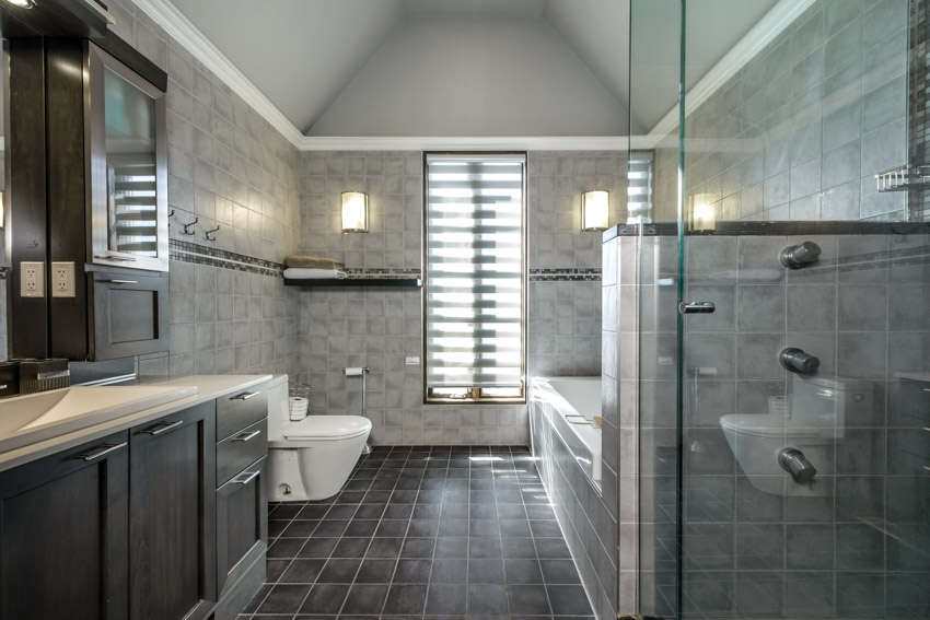 Bathroom with slate tile floor, toilet, countertop, cabinets, and shower area