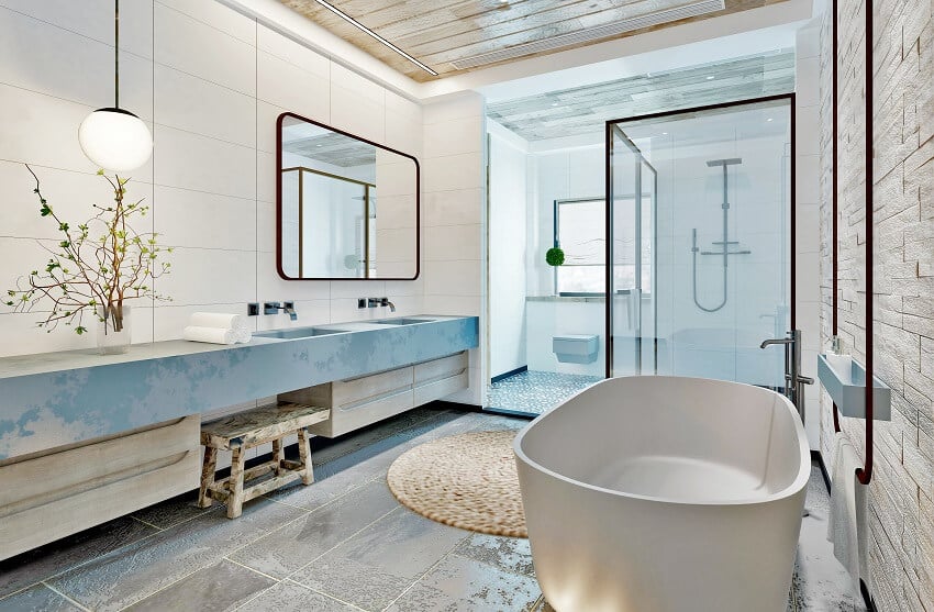 Bathroom with stone and tile wall, pendant light, stone resin bathtub, and tile floor
