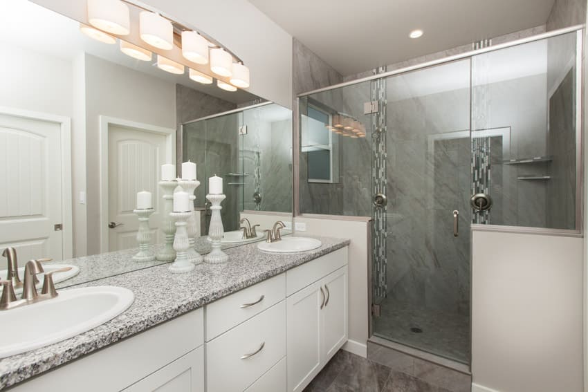 Bathroom with stone resin shower, countertop, sink, glass door, and mirrors