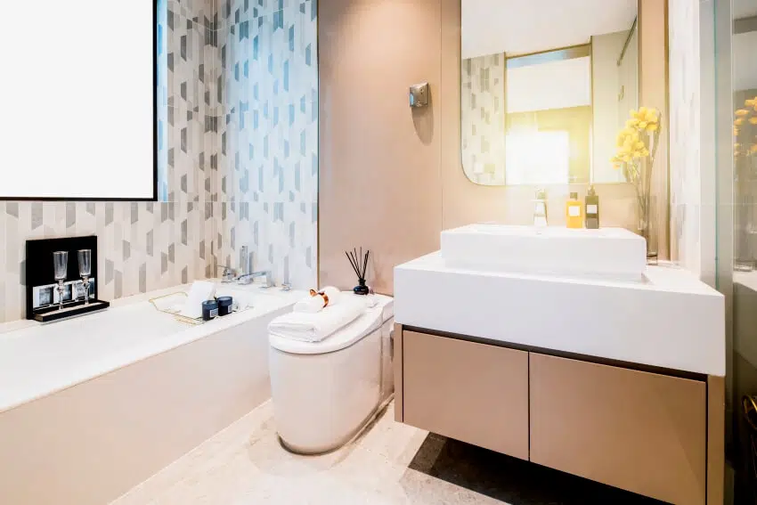 Bathroom with under sink cabinet, patterned wall tile, bathtub, and incinerating toilet