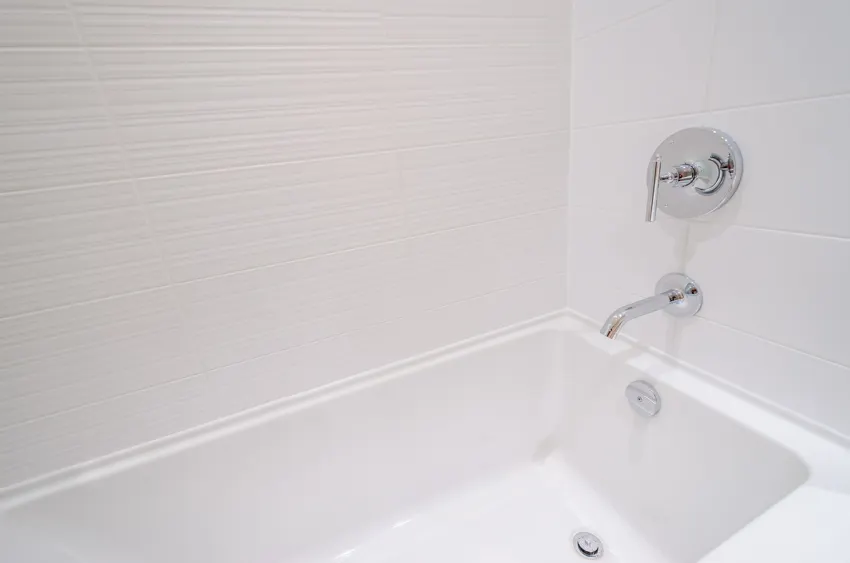 Bathroom with white walls, tub, faucet, and drain