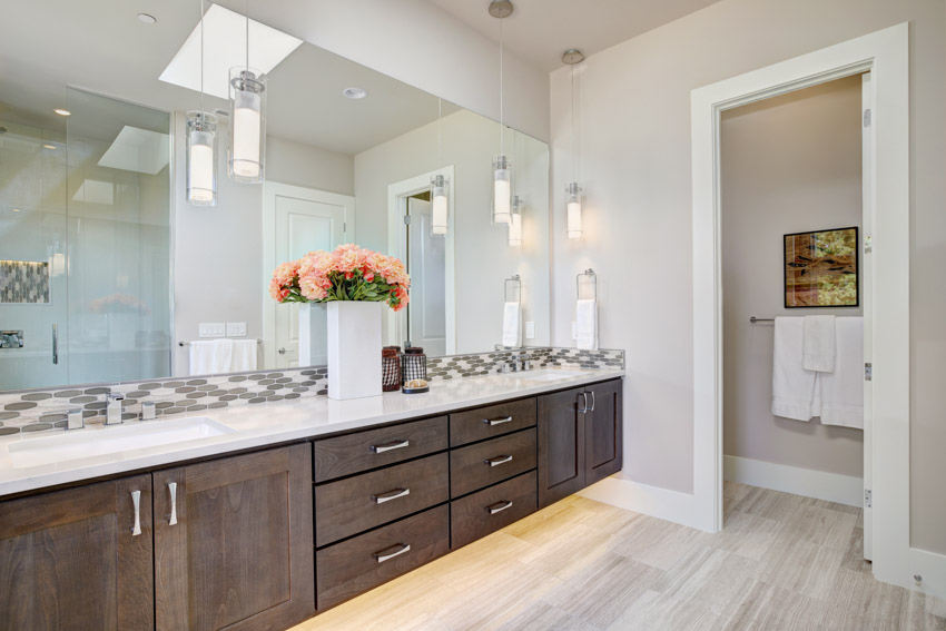 Bathroom with wood cabinets, drawers, laminate floors, mirrors, and countertops
