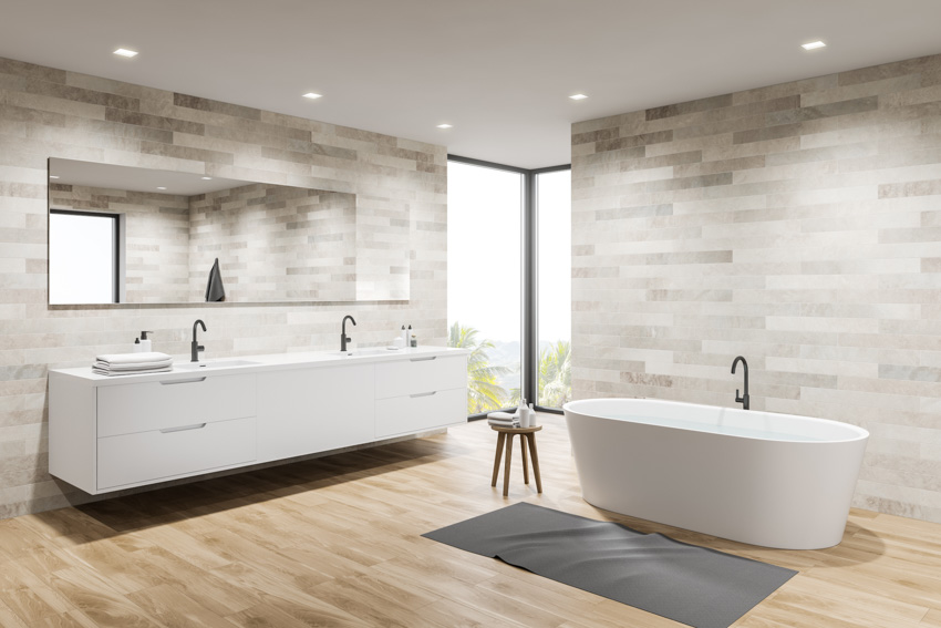 Bathroom with floating vanity. pedestal tub, grey rug and mirror